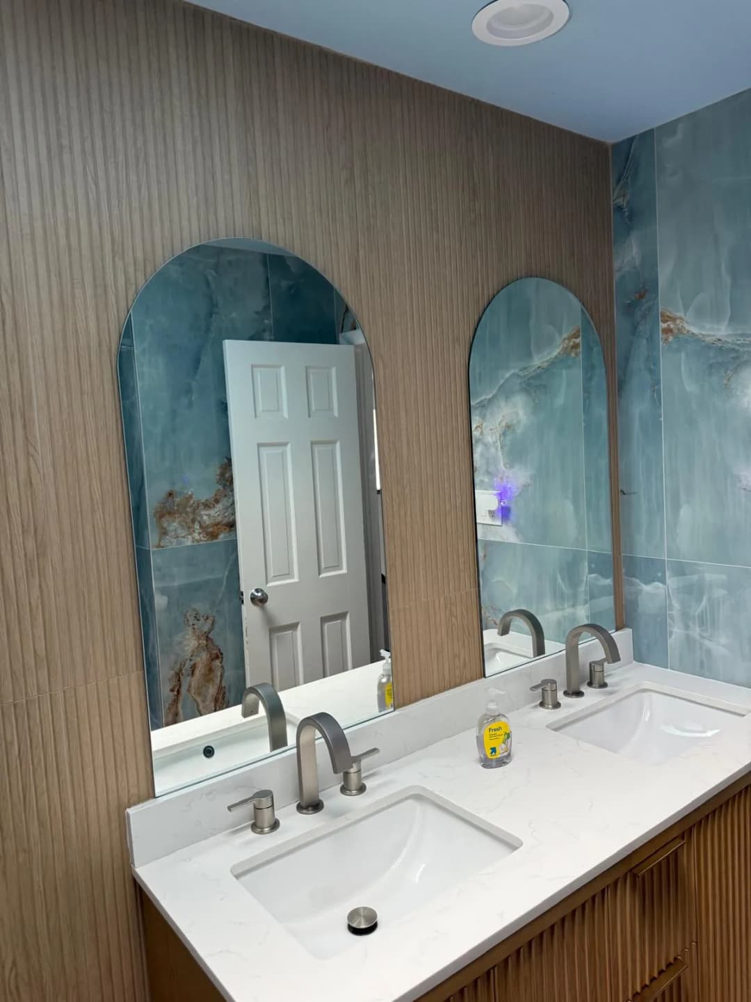 double vanity, arched mirrors, teal onyx accent wall