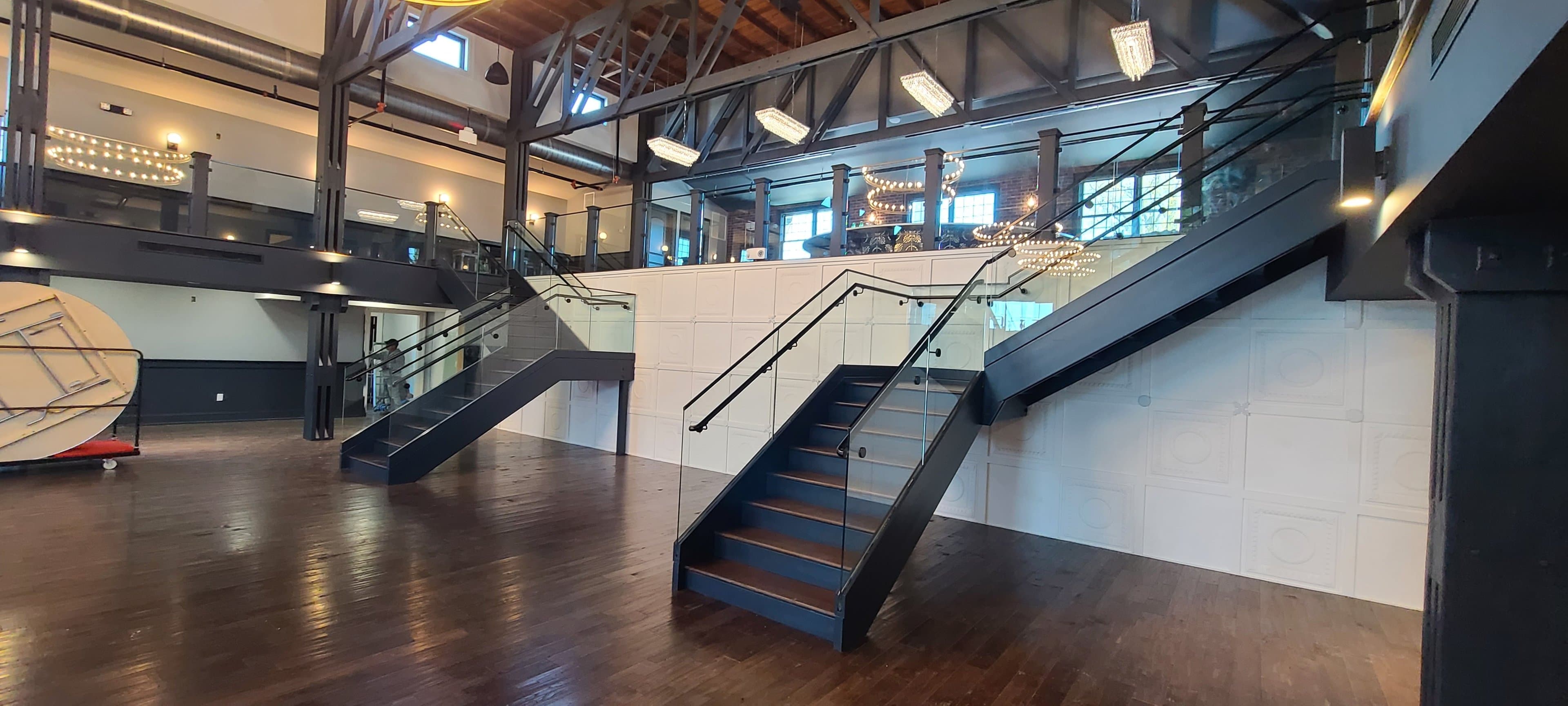 double staircase with glass railings, chandeliers