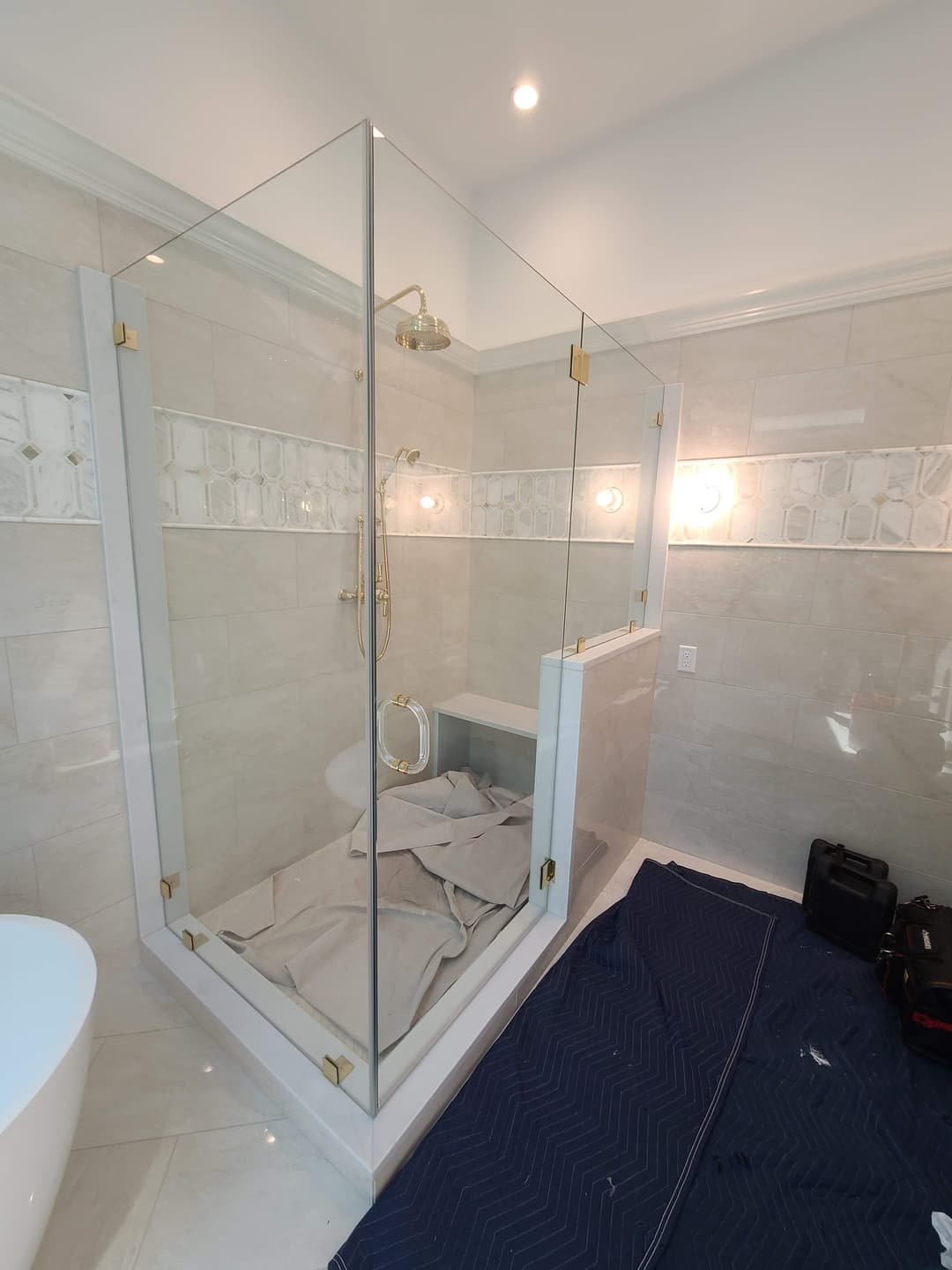 corner glass shower, gold fixtures, tan tile