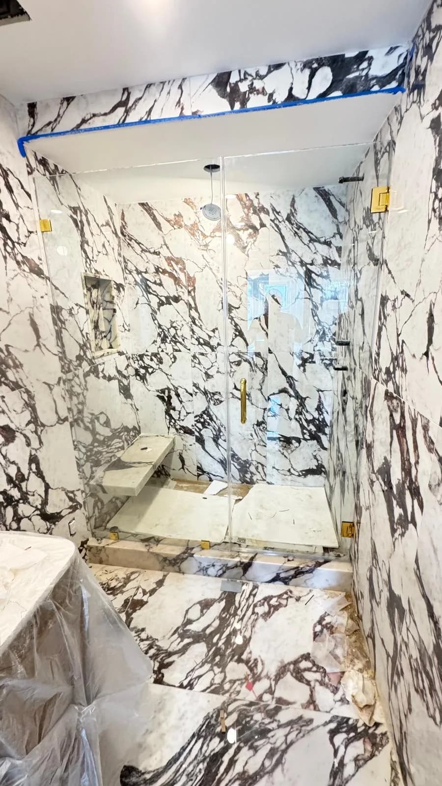 dark marble steam shower, gold hardware, construction stage